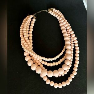 Light baby pink beaded necklace with multiple layers.